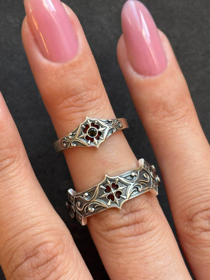 Close-up view of a gothic floral silver ring showcasing a detailed rose-inspired pattern and a polished black gemstone set in the middle. The intricate scrollwork surrounding the stone resembles cathedral tracery, giving the ring an old-world, medieval look. Perfect for engagement, weddings, anniversaries, or collectors of dark romantic jewelry and handcrafted artistic pieces. (etsy image id: 7243100328)