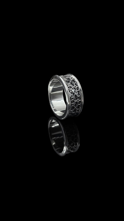 This view focuses on the tactile quality of the 925 sterling silver. The raised lattice framework is smooth and rounded, ensuring it won't snag on clothing, while the black background has a stippled, grainy texture that absorbs light. The image captures the "chiaroscuro" effect of the metalwork—the interplay of light silver and dark shadow—which gives the ring a rugged, masculine feel suitable for daily wear. (etsy image id: 6052185804)