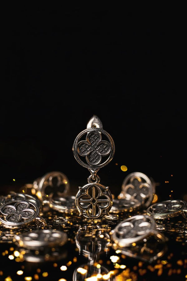 The image highlights the specific textures of the casting. The top stud has a "waffle" or lattice texture inside the quatrefoil lobes, mimicking chainmail or stone carving. The bottom drop is smooth and open, providing a visual counterweight. The 925 sterling silver is treated with an antique patina to enhance the "old world" feel. Modeled as a versatile daily earring, the "coin" size is modest enough for office wear (etsy image id: 5775868859)
