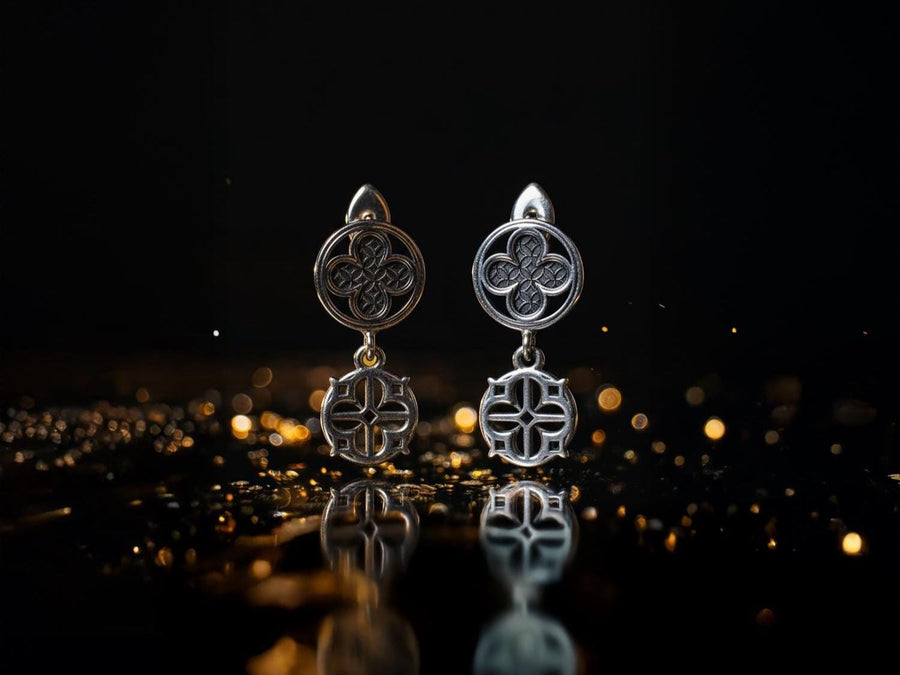 The image highlights the specific textures of the casting. The top stud has a "waffle" or lattice texture inside the quatrefoil lobes, mimicking chainmail or stone carving. The bottom drop is smooth and open, providing a visual counterweight. The 925 sterling silver is treated with an antique patina to enhance the "old world" feel. Modeled as a versatile daily earring, the "coin" size is modest enough for office wear (etsy image id: 5775868859)