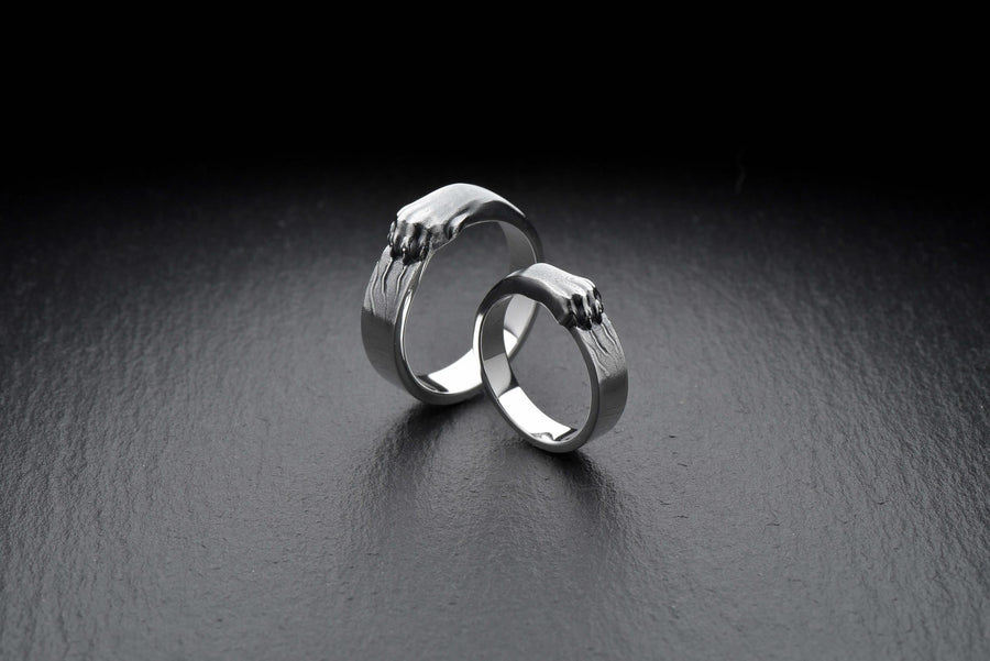 A pair of gothic sterling silver wedding rings featuring sculpted claw details that wrap organically around each band. The dramatic design blends polished metal with textured claw surfaces, creating a symbolic representation of unity and strength. Ideal for alternative couples who appreciate bold artisan jewelry with dark, meaningful aesthetics and handcrafted quality suitable for weddings or promise rings.