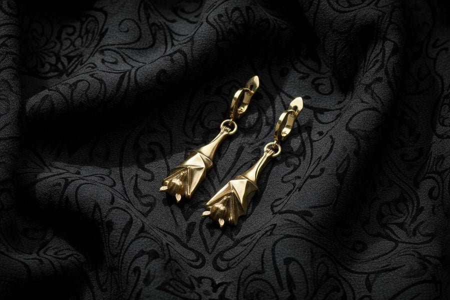 May include: A pair of silver-colored bat-shaped earrings. Each earring features a detailed bat design with outstretched wings and a small loop for attachment. The earrings are suspended from a curved hook. The background is a dark, textured surface. A detailed close-up studio shot of a pair of sterling silver dangle earrings shaped like flying foxes. Each earring features a highly textured sleeping fruit bat hanging upside down, wrapped securely (etsy image id: 7368202736)