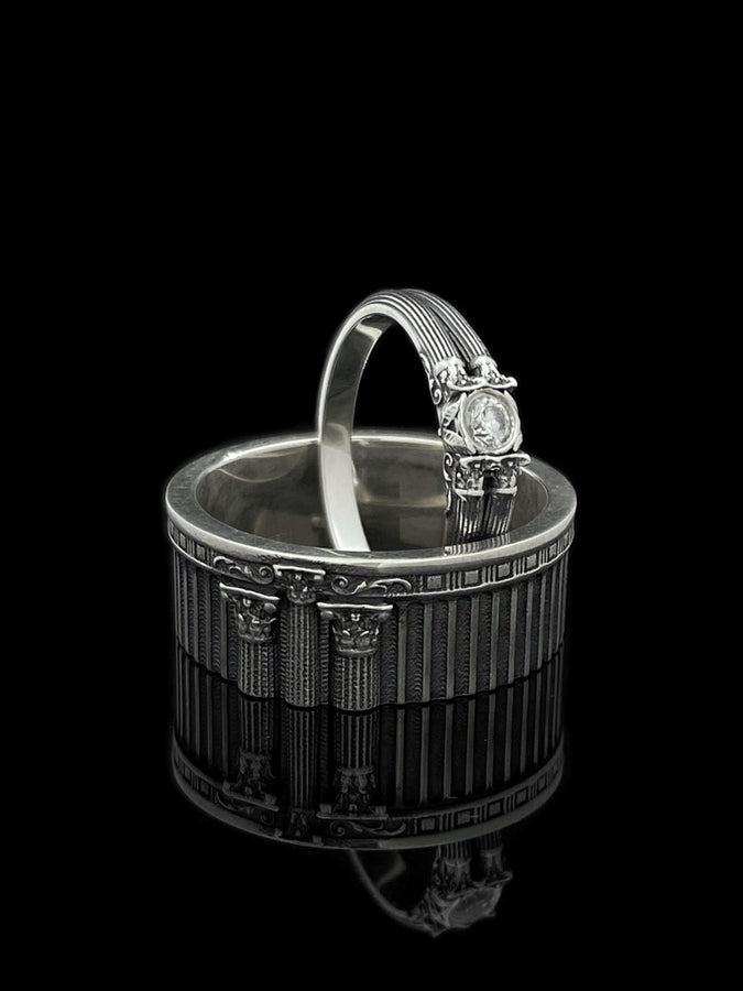 This sterling silver ring set features bold architectural column details with finely carved fluting and ornate capital motifs. The design draws inspiration from ancient Greek and Roman structures, offering a sculptural aesthetic that feels elegant and timeless. Ideal for wedding sets or collectors of detailed art jewelry, the polished silver contrasts beautifully with the deep engraved textures.