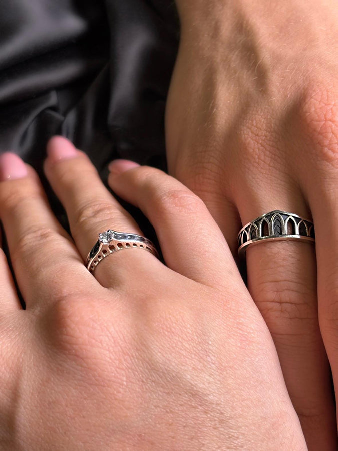 A professional studio photograph of a matching two-piece sterling silver wedding ring set. Both rings feature a prominent, raised Greek-style cross motif in the center, which holds a round, bezel-set white crystal. The interior of the cross arms has a fine, cross-hatched grid texture. Along the sides of the high-polished silver bands are recessed, four-lobed quatrefoil shapes. The rings are presented against a pitch-black background, making the p __etsy:8051335185