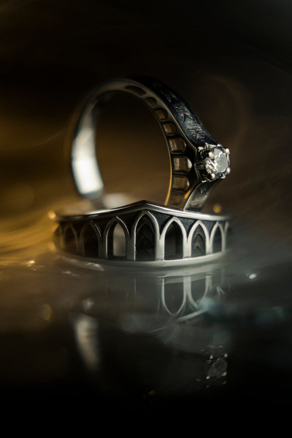 A professional studio photograph of a matching two-piece sterling silver wedding ring set. Both rings feature a prominent, raised Greek-style cross motif in the center, which holds a round, bezel-set white crystal. The interior of the cross arms has a fine, cross-hatched grid texture. Along the sides of the high-polished silver bands are recessed, four-lobed quatrefoil shapes. The rings are presented against a pitch-black background, making the p __etsy:8051335185