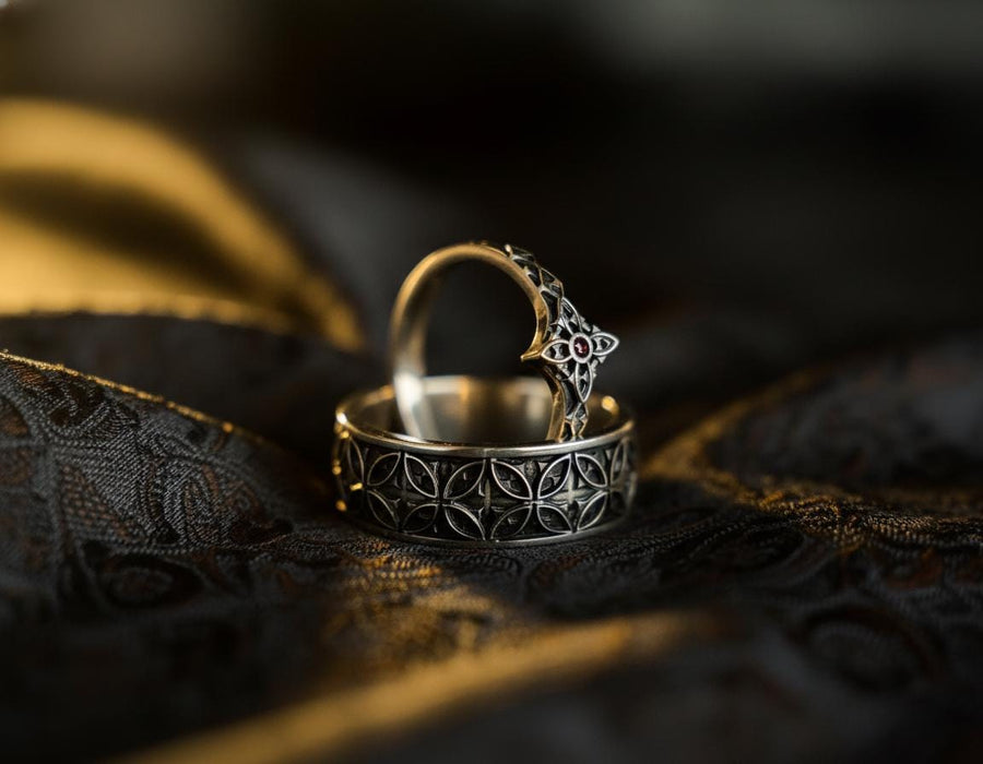 A professional studio photograph of a matching two-piece sterling silver wedding ring set. Both rings feature a prominent, raised Greek-style cross motif in the center, which holds a round, bezel-set white crystal. The interior of the cross arms has a fine, cross-hatched grid texture. Along the sides of the high-polished silver bands are recessed, four-lobed quatrefoil shapes. The rings are presented against a pitch-black background, making the p __etsy:8051335185