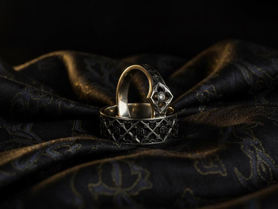 A professional studio photograph of a matching two-piece sterling silver wedding ring set. Both rings feature a prominent, raised Greek-style cross motif in the center, which holds a round, bezel-set white crystal. The interior of the cross arms has a fine, cross-hatched grid texture. Along the sides of the high-polished silver bands are recessed, four-lobed quatrefoil shapes. The rings are presented against a pitch-black background, making the p __etsy:8051335185