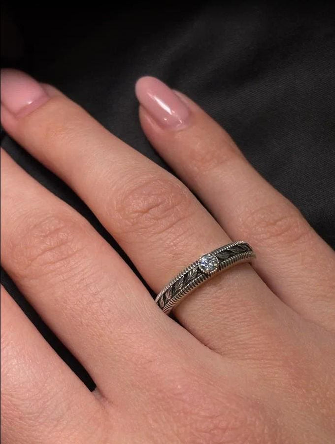A nature-inspired silver wedding ring featuring raised leaf motifs and a shimmering round gemstone set in the center. The Art Nouveau style is expressed through smooth curves and organic detailing along the band. Ideal for brides or grooms who appreciate delicate plant symbolism, handcrafted jewelry, and an elegant blend of vintage and contemporary design elements in their wedding set. (etsy image id: 6300134508)