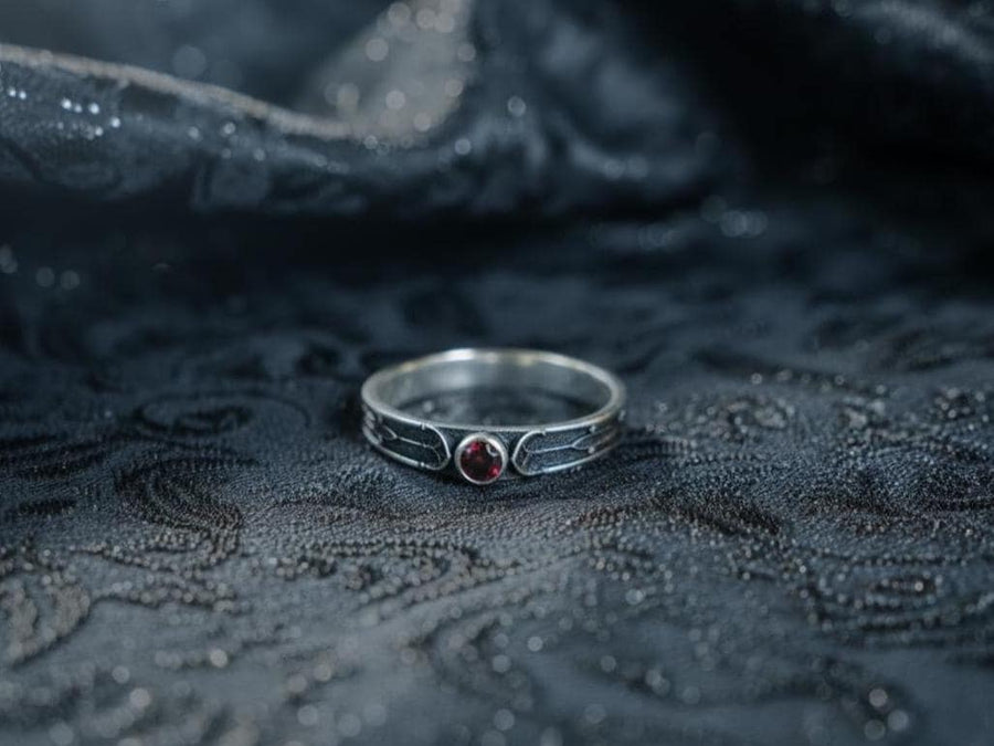 This gothic sterling silver ring features a vivid red garnet set in a detailed medieval-inspired band with darkened textures and graceful, pointed motifs. Designed for lovers of fantasy, gothic fashion, and artisan jewelry, it offers an elegant yet dramatic look. Perfect as a unique wedding band, engagement ring, or statement piece for anyone drawn to symbolic and timeless gothic style. (etsy image id: 7425901470)