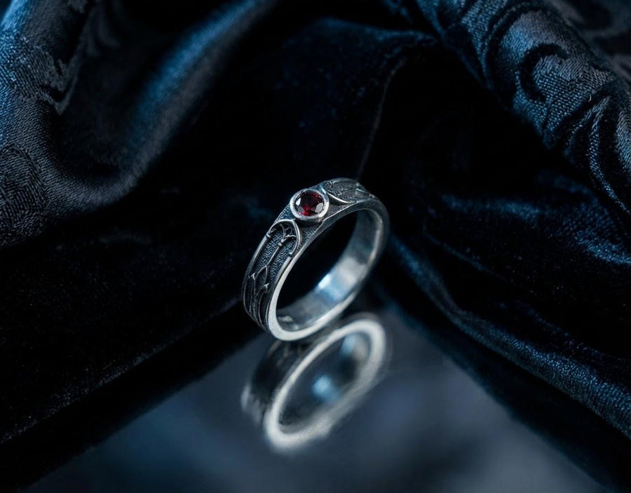 This gothic sterling silver ring features a vivid red garnet set in a detailed medieval-inspired band with darkened textures and graceful, pointed motifs. Designed for lovers of fantasy, gothic fashion, and artisan jewelry, it offers an elegant yet dramatic look. Perfect as a unique wedding band, engagement ring, or statement piece for anyone drawn to symbolic and timeless gothic style. (etsy image id: 7425901470)