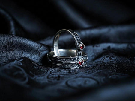 A detailed gothic wedding ring set crafted in sterling silver, featuring sharp architectural lines, dark textured surfaces, and deep red gemstones. The design blends medieval fantasy aesthetics with fine jewelry craftsmanship, creating a dramatic alternative bridal look. Ideal for couples wanting a unique, symbolic set with rich character and bold visual presence.
