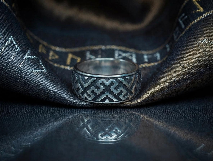 A detailed profile shot of a wide sterling silver ring featuring a repeating "step" or "zig-zag" pattern. The design wraps seamlessly around the entire band. The raised geometric lines are highly polished, catching the light, while the recessed areas are treated with a matte black oxidation. This creates a high-contrast, graphic look similar to a digital pixel pattern or traditional cross-stitch embroidery. (etsy image id: 7438608638)