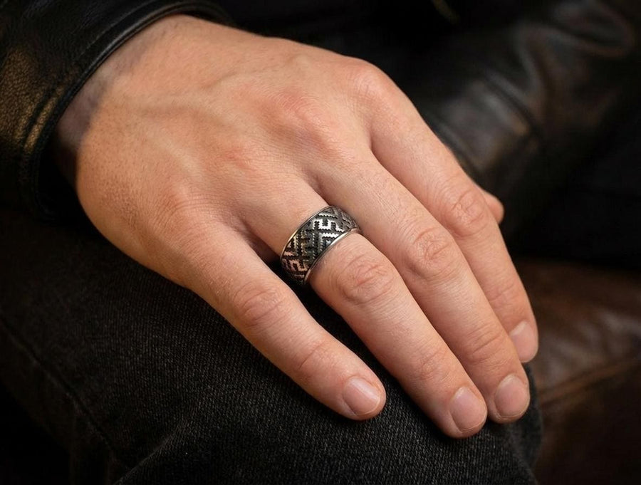 A detailed profile shot of a wide sterling silver ring featuring a repeating "step" or "zig-zag" pattern. The design wraps seamlessly around the entire band. The raised geometric lines are highly polished, catching the light, while the recessed areas are treated with a matte black oxidation. This creates a high-contrast, graphic look similar to a digital pixel pattern or traditional cross-stitch embroidery. (etsy image id: 7438608638)