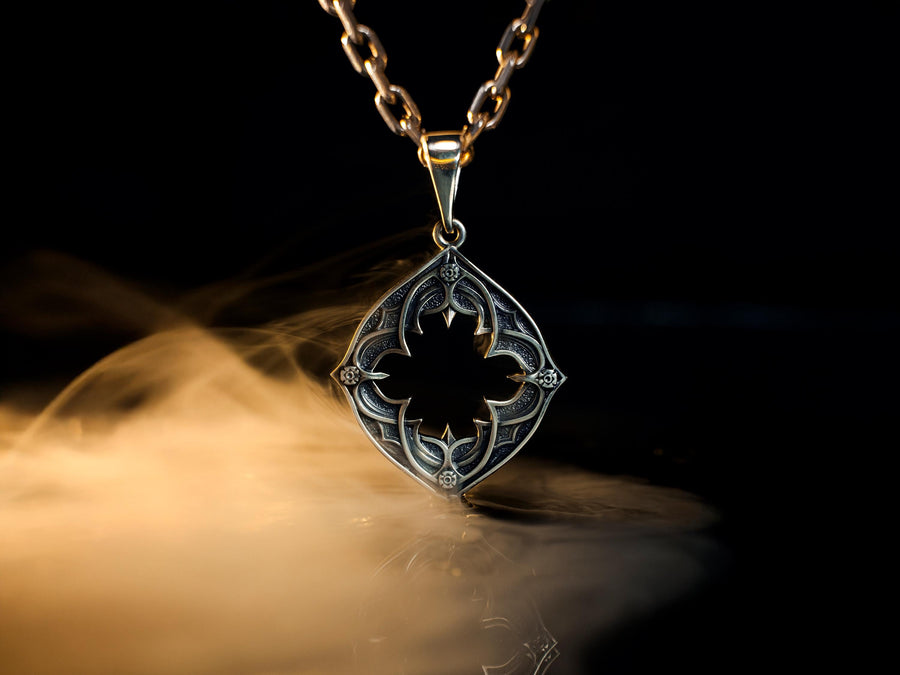 Sterling Silver Gothic Pendant, Holiday Gift, Handmade Medieval Pendant, Goth Necklace, Gothic Jewelry, A cinematic studio shot of a diamond-shaped sterling silver pendant hanging against a smoky, amber-lit background. The design is "openwork," featuring a central cutout in the shape of a four-lobed quatrefoil with sharp, barbed cusps. The silver frame mimics the stone mullions of a Gothic window. The metal is polished on the ridges and (etsy image id: 6258009905)