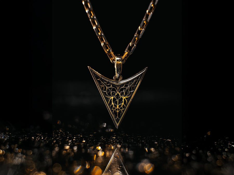 A detailed studio shot of an inverted triangle-shaped pendant hanging from a sturdy chain. The design features a "V" shape frame filled with complex, organic filigree. The inner pattern resembles branching roots, veins, or the "Flamboyant" style of late Gothic window tracery. The raised silver lines are polished bright, contrasting with the matte black oxidation in the negative spaces. (etsy image id: 7496362357)