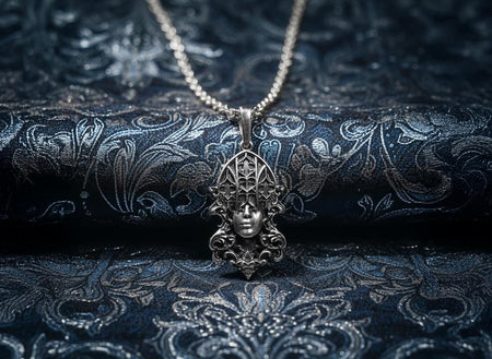 A detailed studio shot of a sterling silver pendant resting on a dark, textured stone surface. The design features a realistic human face in the center, but the forehead and eyes are obscured by a grid of Gothic window tracery (vertical bars and trefoils). The chin is framed by swirling Art Nouveau-style acanthus leaves. The silver is heavily oxidized, giving the face the appearance of a weathered stone statue. (etsy image id: 7448678222)