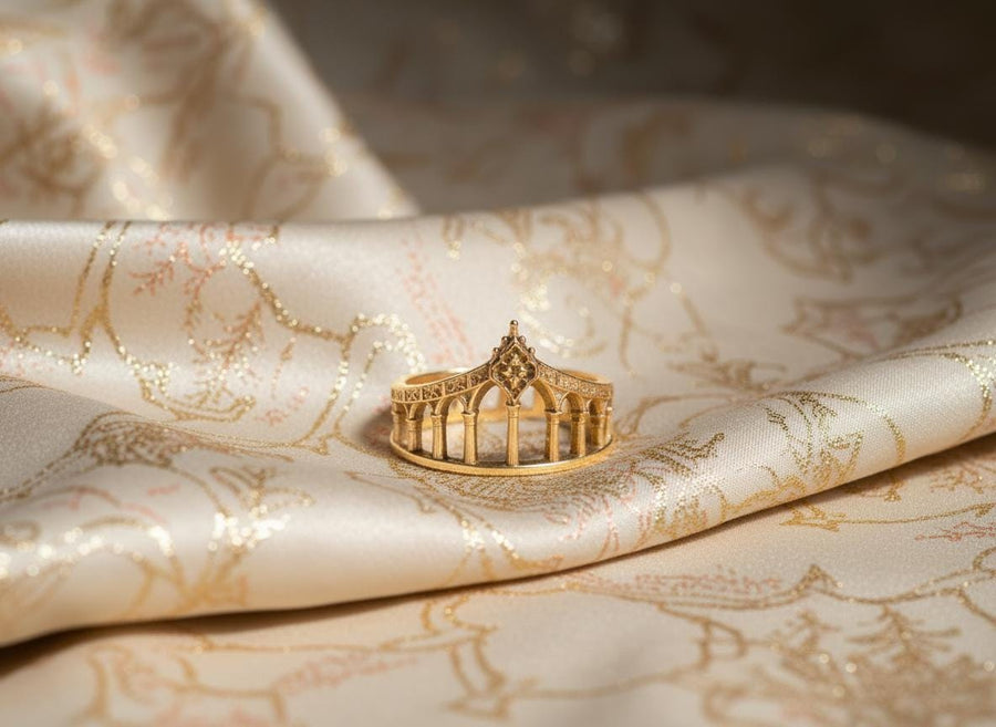 A cinematic studio shot of a sculptural sterling silver ring standing in shallow water. The design mimics a bridge or aqueduct, featuring a row of vertical pillars or columns that support a rising upper rail. The center rises to a sharp point adorned with a floral or quatrefoil relief. The space between the columns is open, creating a "see-through" architectural silhouette. (etsy image id: 7450247674)