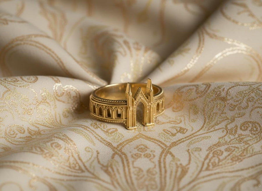 A cinematic studio shot of a sculptural sterling silver ring standing on a reflective surface. The design mimics the facade of a Gothic cathedral or castle gate. Two tall, pointed spires rise up on either side of a central archway. The band continues outwards with a colonnade of smaller arches. The silver features a beaded "cornice" detail along the edges and is heavily oxidized to emphasize the depth of the "stonework." (etsy image id: 7450300962)