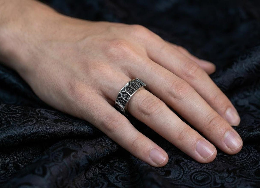 Defend your realm with this architectural fortress ring. Distinctive for its soft-square outer profile, this sterling silver band features a continuous cloister of Gothic arches anchored by robust corner buttresses. The geometric design mimics the stone ramparts of a medieval castle. Heavily oxidized to reveal the depth of the masonry, it is a symbol of unshakeable strength and structure. A bold statement for the guardian of history. (etsy image id: 7450412634)