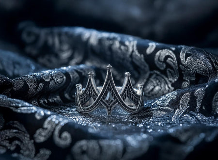 A detailed studio shot of a "crown-style" sterling silver ring resting on a dark surface. The band is formed by a series of high, pointed arches or chevrons that encircle the finger. The interior of each triangular peak is filled with a cross-hatched lattice texture, heavily oxidized to black. The borders and tips of the spires are polished smooth silver. (etsy image id: 7452333496)