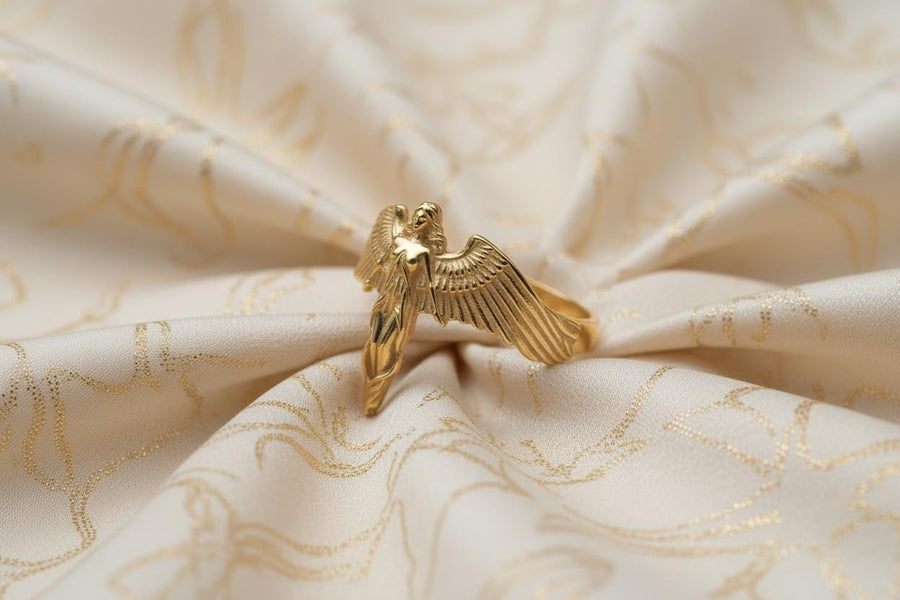 A clear studio shot of a sculptural sterling silver ring on a white background. The ring features a full-body female figure, likely an angel or goddess, positioned at the center. Her large, detailed wings spread horizontally to form the top half of the ring band. Her dress flows downward, tapering into the bottom of the band. (etsy image id: 7500519831)