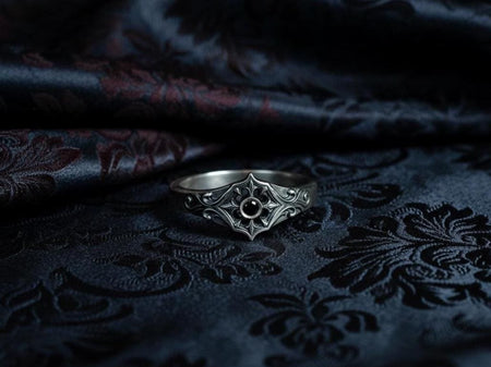 A sterling silver gothic engagement ring featuring an ornate floral motif with swirling filigree and a dark round gemstone at the center. The ring’s rich medieval character is enhanced by its sculpted rose details, antique texturing, and elegant symmetry. Ideal for gothic brides, alternative fashion lovers, or anyone seeking a unique, dramatic piece of romantic jewelry. (etsy image id: 7475048463)
