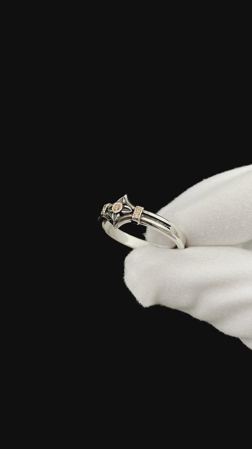 A macro photograph of a sterling silver ring with a distinct medieval silhouette. The centerpiece is a four-pointed "cross" or "star" shape holding a round, amber-hued gemstone (Citrine). The band is flanked by small, vertical bars set with tiny accent stones that sparkle in the light. The metal features a mix of high-polish highlights and dark, oxidized recesses, giving it an antique, artifact-like appearance. (etsy image id: 7488715953)