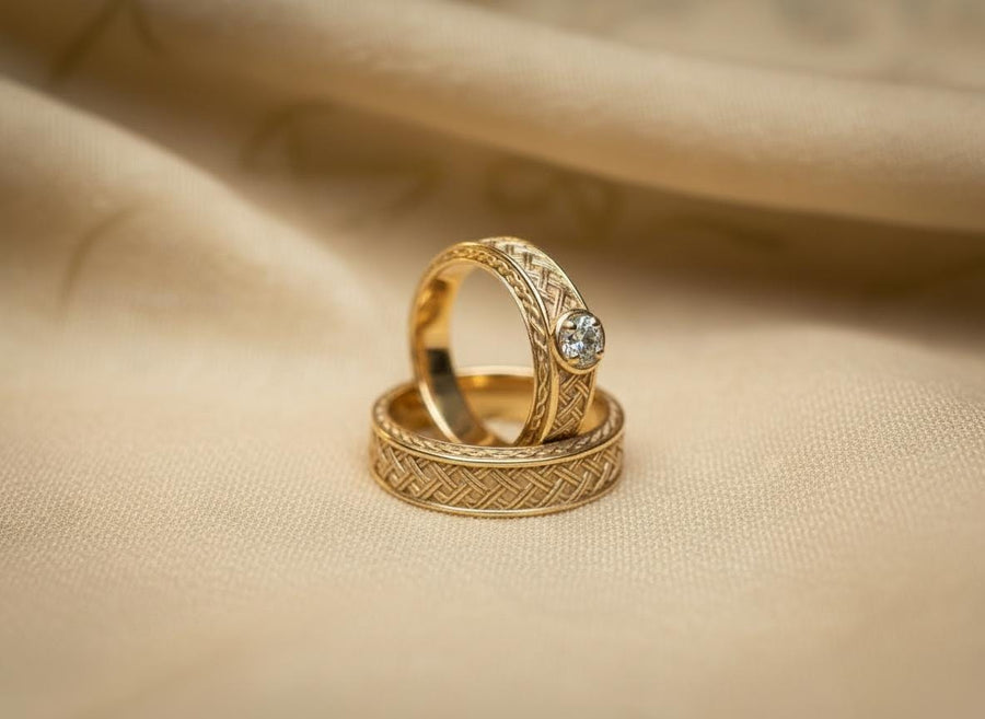 A warm, atmospheric shot of a matching wedding ring set. The engagement ring stands upright, showcasing a round white gemstone in a bezel setting. Lying flat beneath it is a matching wide band without a stone. Both rings share a cohesive design: a central diagonal "basket weave" pattern flanked by twisted rope borders. The silver is oxidized to reveal the intricate texture of the weave.