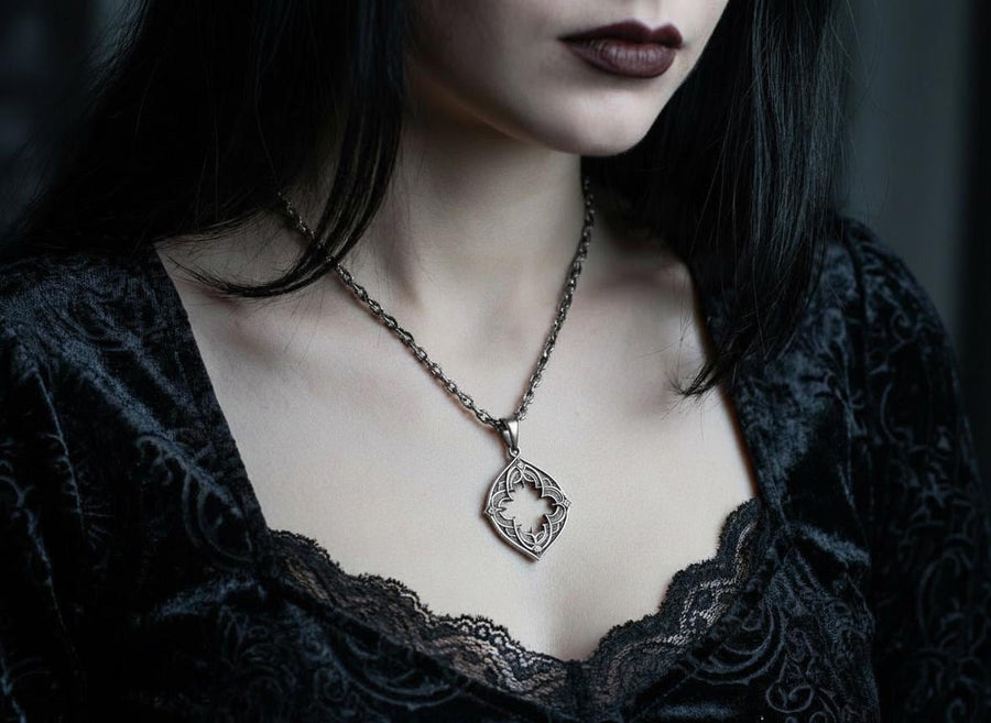 Sterling Silver Gothic Pendant, Holiday Gift, Handmade Medieval Pendant, Goth Necklace, Gothic Jewelry, A cinematic studio shot of a diamond-shaped sterling silver pendant hanging against a smoky, amber-lit background. The design is "openwork," featuring a central cutout in the shape of a four-lobed quatrefoil with sharp, barbed cusps. The silver frame mimics the stone mullions of a Gothic window. The metal is polished on the ridges and (etsy image id: 6258009905)