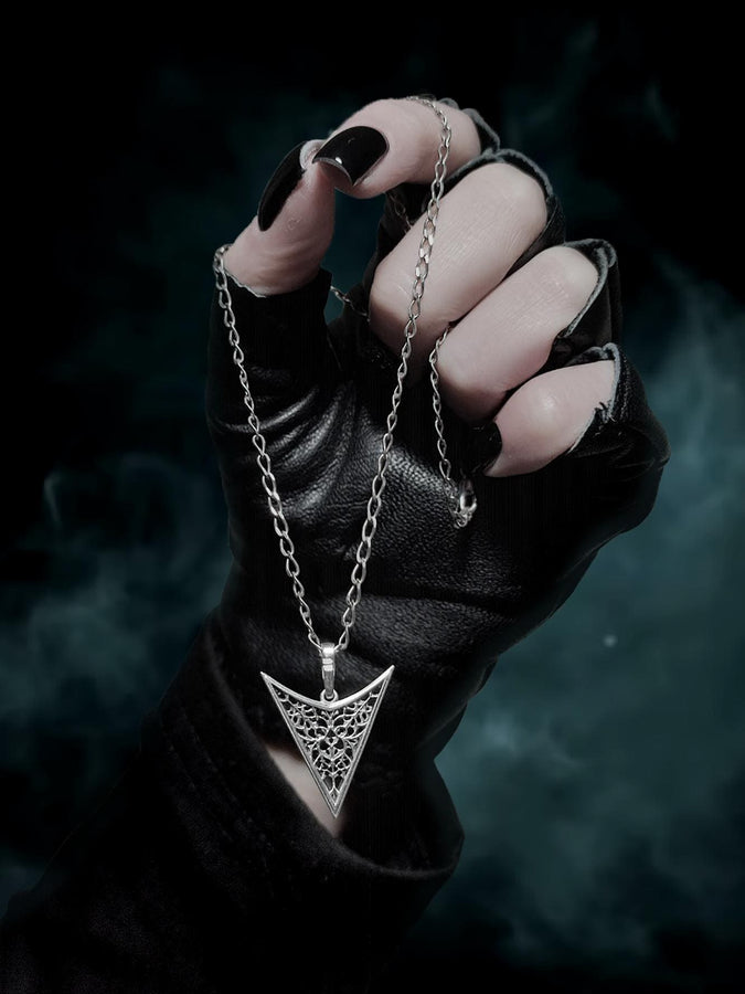 A detailed studio shot of an inverted triangle-shaped pendant hanging from a sturdy chain. The design features a "V" shape frame filled with complex, organic filigree. The inner pattern resembles branching roots, veins, or the "Flamboyant" style of late Gothic window tracery. The raised silver lines are polished bright, contrasting with the matte black oxidation in the negative spaces. (etsy image id: 7496362357)