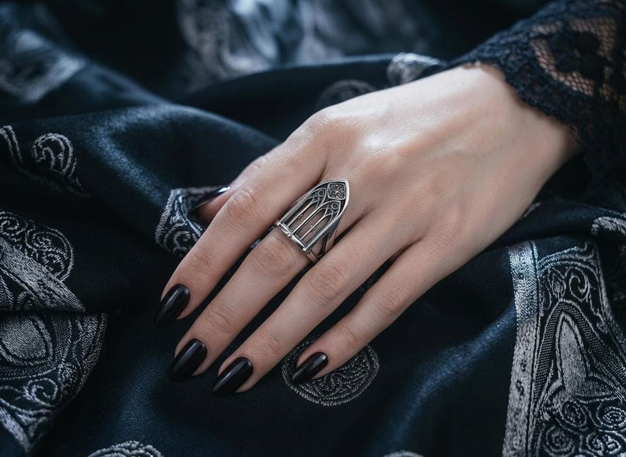 A clean studio shot of a tall, architectural sterling silver ring standing on a matte grey surface. The ring creates the silhouette of a Gothic "Lancet Window." It features three vertical openings separated by slender bars (mullions), topped by an intricate geometric tracery design within the pointed arch. The metal is matte silver with dark oxidation in the corners. (etsy image id: 7500328125)