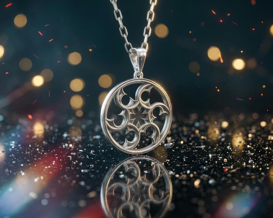 A detailed close-up of a circular sterling silver pendant resting on a dark blue, textured silk fabric. The pendant features an openwork design with swirling, crescent-like shapes radiating from a central four-pointed star. The intricate pattern resembles a gothic rose window or a celestial wheel. The raised metal surfaces are polished to a bright silver shine, contrasting beautifully against the dark, oxidized background recesses. (etsy image id: 7830974908)