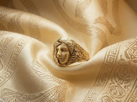 Reimagined in solid 14k yellow gold, this fractured Athena ring transforms from a brooding stone artifact into a corrupted imperial treasure. The warm, radiant metal makes the smooth half of the goddess's face gleam with classical opulence, while the eroded, brutalist half looks like molten gold or a relic salvaged from a volcanic ruin. The dark oxidation in the central crack creates a striking, high-contrast rift. This version is the ultimat (etsy image id: 7831403894)