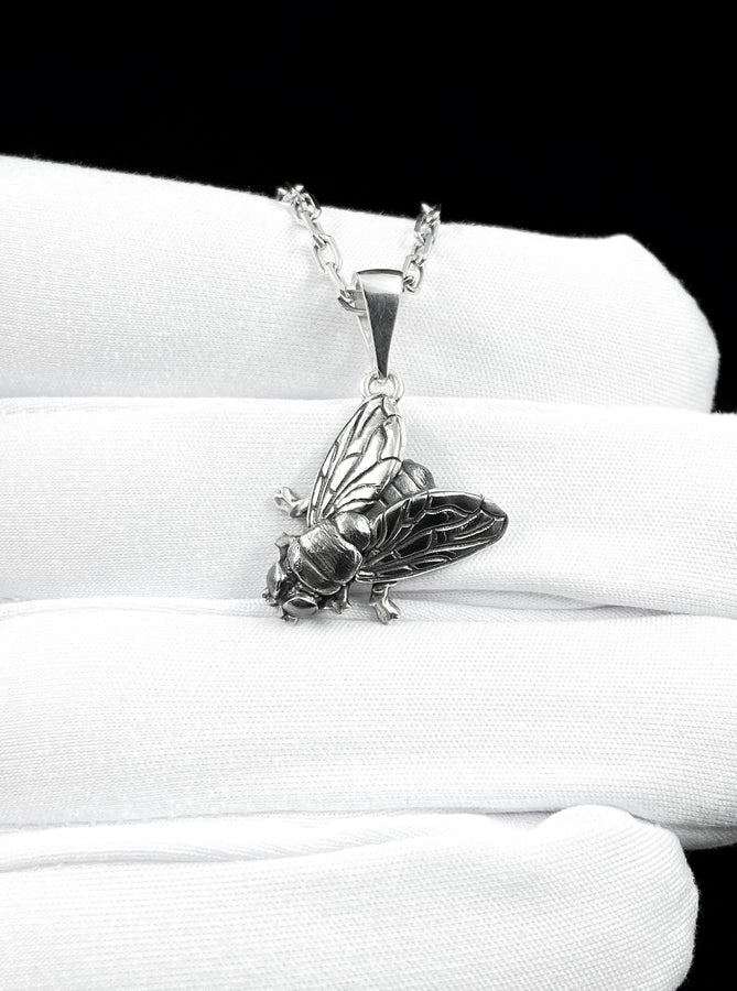 May include: A silver-colored pendant necklace featuring a detailed insect design. The pendant depicts a cicada with intricate wing and body details, suspended from a delicate chain. The necklace is displayed against a white background.
