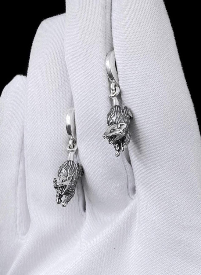 A close-up studio shot of sterling silver dangle earrings featuring detailed opossums. The animals are depicted with open mouths and textured fur, hanging from polished lever-back clasps. The metal is heavily oxidized in the recesses to enhance the realistic, rugged appearance of the marsupials against a white fabric background.