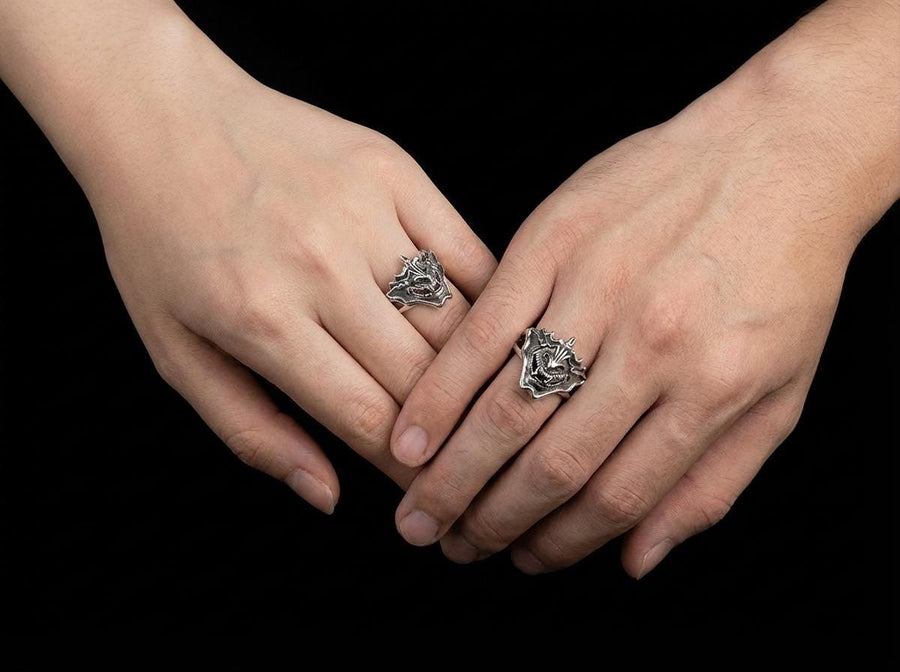 A close-up studio shot of a sterling silver ring featuring a detailed Japanese Oni mask. The demon face has sharp fangs, a wide menacing grin, and two distinct horns protruding from its forehead. The band features openwork cutouts on the sides, merging seamlessly with the mask. The metal is heavily oxidized to a dark charcoal in the recesses, making the highly polished silver ridges of the fierce expression pop against the dark reflective backgro (etsy image id: 7959798327)