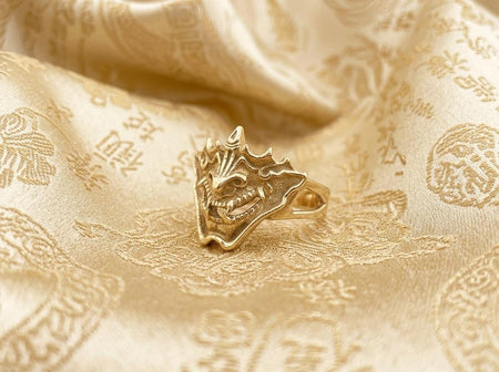 Reimagined in solid 14k yellow gold, this fierce Oni mask ring transforms from a dark gothic accessory into an opulent, imperial treasure. The warm golden metal softens the brutalist fangs and horns, highlighting the intricate facial details with a luxurious, regal glow reminiscent of antique samurai armor. The deep recesses feature a soft matte finish rather than black oxidation. This magnificent fine jewelry version elevates the mythical motif. (etsy image id: 7911858220)