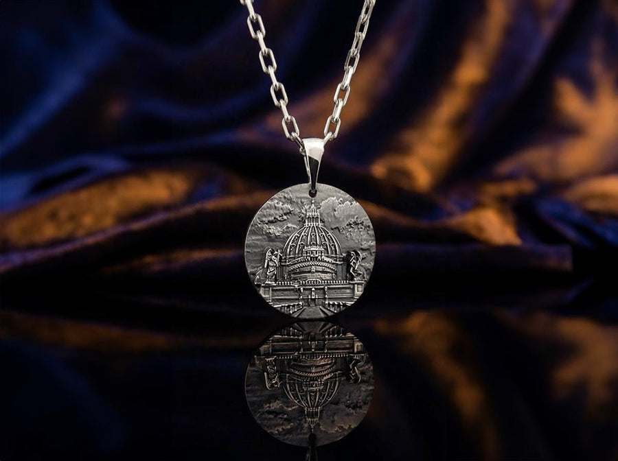 A high-resolution studio photograph of a circular sterling silver pendant suspended from a sturdy chain. The face of the medallion features a highly detailed, three-dimensional bas-relief carving of the Castle of the Holy Angel (Castel Sant'Angelo). The intricate architecture, including the grand dome, colonnades, and angel statues, is polished to a bright shine, while the background sky and recesses are heavily oxidized to a dark matte gray, (etsy image id: 7912107724)