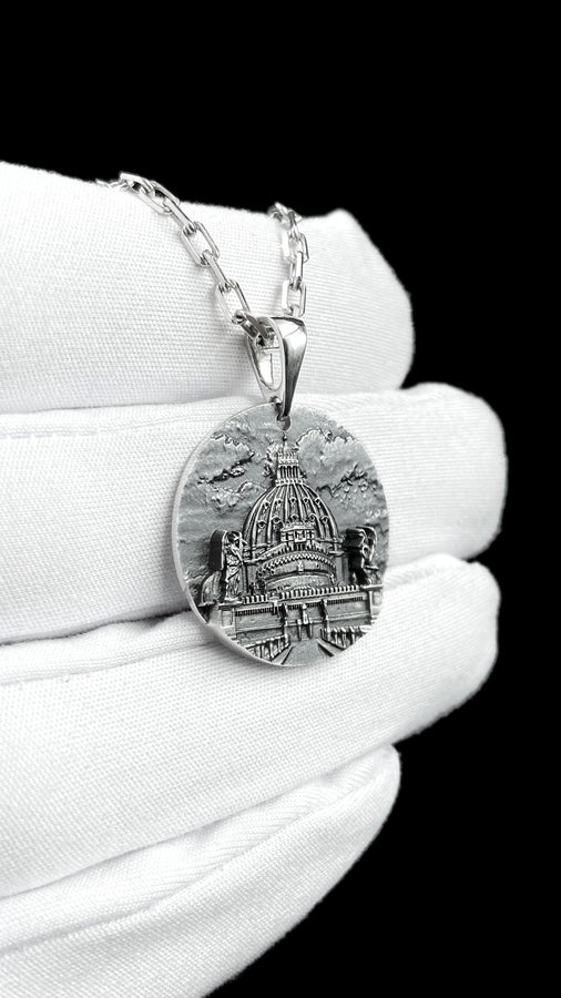 A high-resolution studio photograph of a circular sterling silver pendant suspended from a sturdy chain. The face of the medallion features a highly detailed, three-dimensional bas-relief carving of the Castle of the Holy Angel (Castel Sant'Angelo). The intricate architecture, including the grand dome, colonnades, and angel statues, is polished to a bright shine, while the background sky and recesses are heavily oxidized to a dark matte gray, (etsy image id: 7912107724)