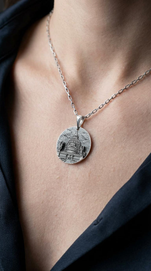 A high-resolution studio photograph of a circular sterling silver pendant suspended from a sturdy chain. The face of the medallion features a highly detailed, three-dimensional bas-relief carving of the Castle of the Holy Angel (Castel Sant'Angelo). The intricate architecture, including the grand dome, colonnades, and angel statues, is polished to a bright shine, while the background sky and recesses are heavily oxidized to a dark matte gray, (etsy image id: 7912107724)