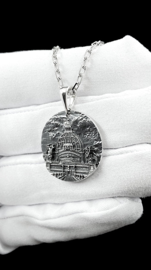 A high-resolution studio photograph of a circular sterling silver pendant suspended from a sturdy chain. The face of the medallion features a highly detailed, three-dimensional bas-relief carving of the Castle of the Holy Angel (Castel Sant'Angelo). The intricate architecture, including the grand dome, colonnades, and angel statues, is polished to a bright shine, while the background sky and recesses are heavily oxidized to a dark matte gray, (etsy image id: 7912107724)
