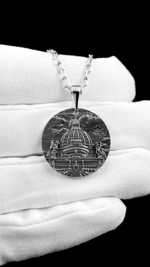 A high-resolution studio photograph of a circular sterling silver pendant suspended from a sturdy chain. The face of the medallion features a highly detailed, three-dimensional bas-relief carving of the Castle of the Holy Angel (Castel Sant'Angelo). The intricate architecture, including the grand dome, colonnades, and angel statues, is polished to a bright shine, while the background sky and recesses are heavily oxidized to a dark matte gray, (etsy image id: 7912107724)