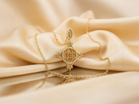 Reimagined in solid 14k yellow gold, this gothic cross pendant transforms from a brooding stone sanctuary into a radiant, museum-quality reliquary. The warm gold illuminates the intricate quatrefoil tracery and slender arches, giving the architectural relief an opulent, regal glow reminiscent of precious medieval church treasures. The brushed matte finish elevates this historical motif into a luxurious fine jewelry masterpiece. (etsy image id: 7979094362)
