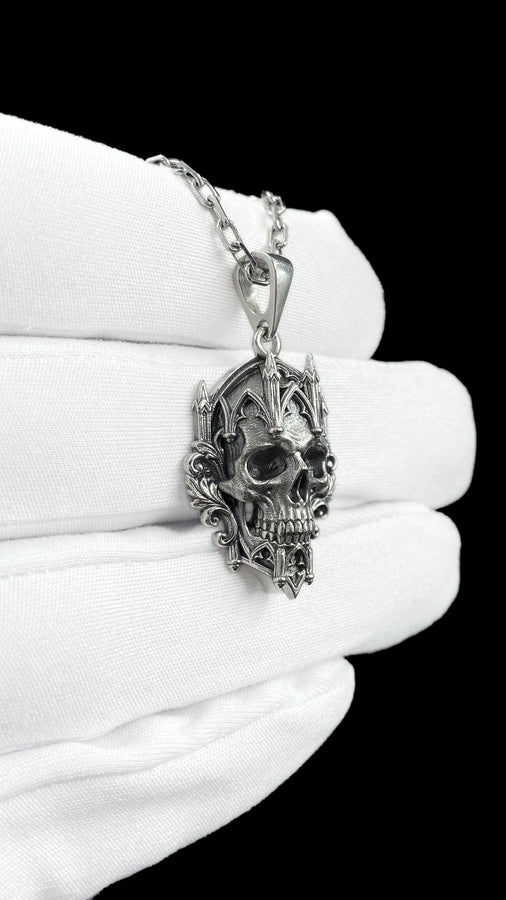 This macro image highlights the masterful texturing of the solid 925 sterling silver casting. The artisan has beautifully captured the smooth, anatomical curves of the organic skull, contrasting them against the rigid, geometric lines of the gothic tracery and cathedral spires. A deep sulfur patina treatment provides permanent matte black shadows, giving this wearable sculpture the rugged, weathered patina of a genuine historical artifact. (etsy image id: 7979410208)