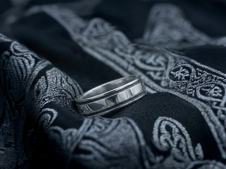 A professional studio photograph of a matching two-piece sterling silver wedding ring set. Both rings feature a prominent, raised Greek-style cross motif in the center, which holds a round, bezel-set white crystal. The interior of the cross arms has a fine, cross-hatched grid texture. Along the sides of the high-polished silver bands are recessed, four-lobed quatrefoil shapes. The rings are presented against a pitch-black background, making the p __etsy:8051335185