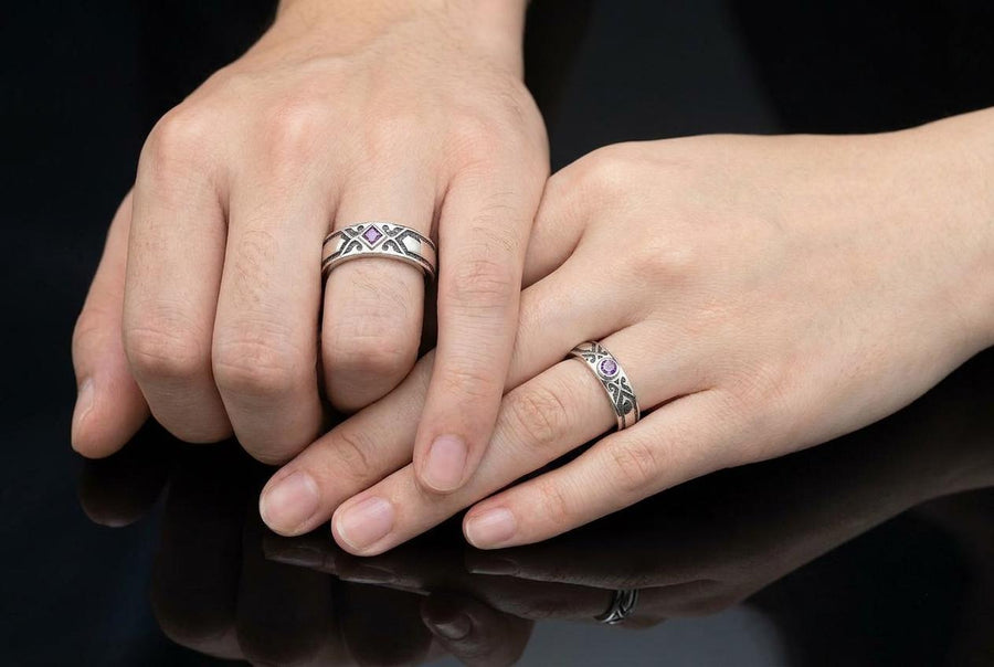 A professional studio photograph of a matching two-piece sterling silver wedding ring set. Both rings feature a prominent, raised Greek-style cross motif in the center, which holds a round, bezel-set white crystal. The interior of the cross arms has a fine, cross-hatched grid texture. Along the sides of the high-polished silver bands are recessed, four-lobed quatrefoil shapes. The rings are presented against a pitch-black background, making the p __etsy:8051335185