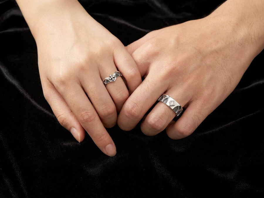 A professional studio photograph of a matching two-piece sterling silver wedding ring set. Both rings feature a prominent, raised Greek-style cross motif in the center, which holds a round, bezel-set white crystal. The interior of the cross arms has a fine, cross-hatched grid texture. Along the sides of the high-polished silver bands are recessed, four-lobed quatrefoil shapes. The rings are presented against a pitch-black background, making the p __etsy:8051335185