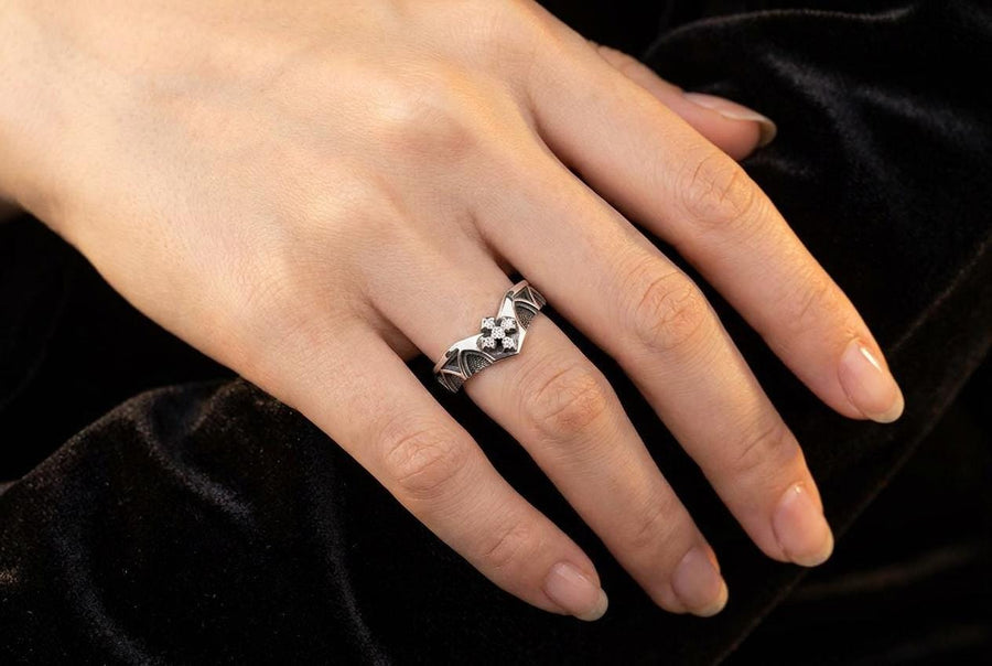 A professional studio photograph of a matching two-piece sterling silver wedding ring set. Both rings feature a prominent, raised Greek-style cross motif in the center, which holds a round, bezel-set white crystal. The interior of the cross arms has a fine, cross-hatched grid texture. Along the sides of the high-polished silver bands are recessed, four-lobed quatrefoil shapes. The rings are presented against a pitch-black background, making the p __etsy:8051335185