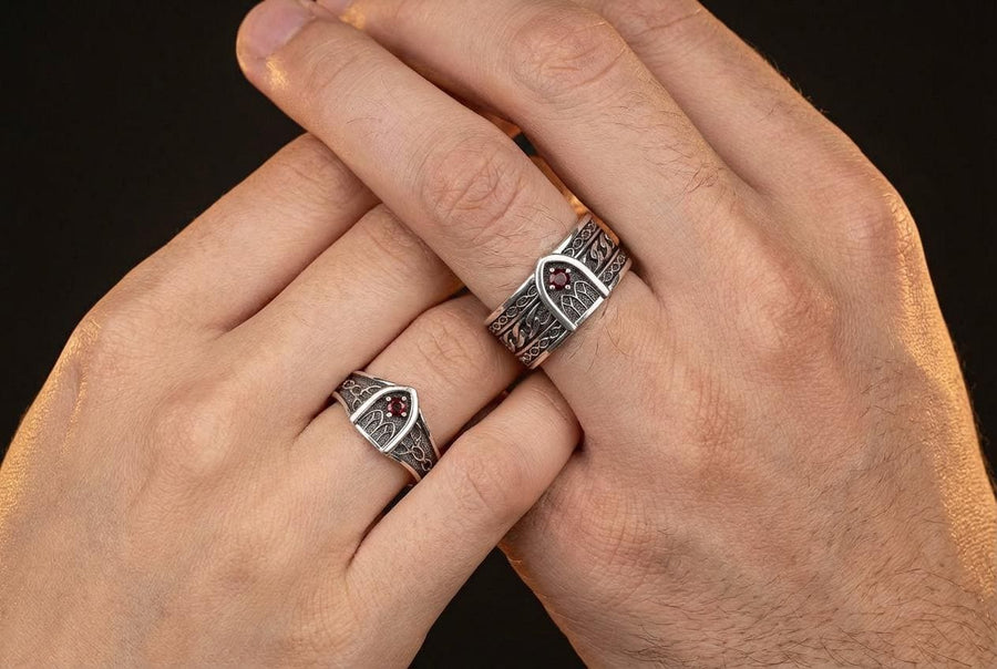 A professional studio photograph of a matching two-piece sterling silver wedding ring set. Both rings feature a prominent, raised Greek-style cross motif in the center, which holds a round, bezel-set white crystal. The interior of the cross arms has a fine, cross-hatched grid texture. Along the sides of the high-polished silver bands are recessed, four-lobed quatrefoil shapes. The rings are presented against a pitch-black background, making the p __etsy:8051335185
