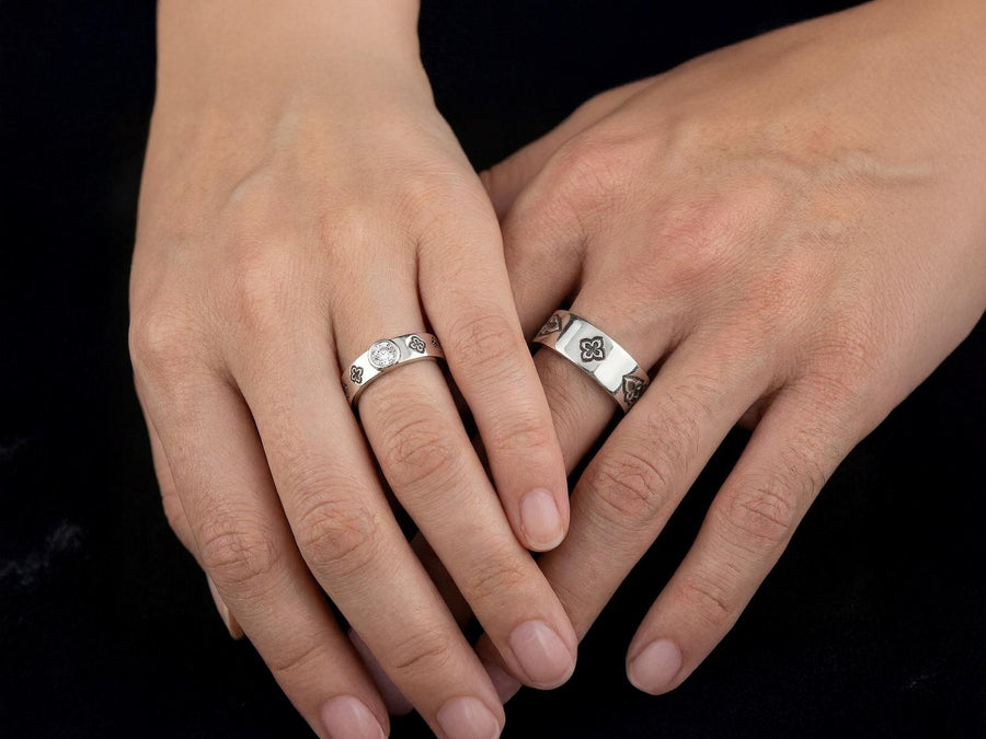This dark academic ring set captures the mysterious romance of a medieval cathedral. Bright studio lighting highlights the polished silver rims, contrasting dramatically with the pitch-black sulfur oxidation in the carved quatrefoil recesses. Rich in gothic symbolism, the continuous quatrefoil motif represents the intersection of earth and heaven, mirroring the windows of ancient cathedrals. It serves as a profound talisman of eternal devotion an